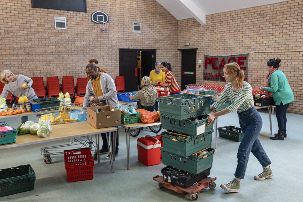 Group of volunteers organising food donations onto tables at a food bank