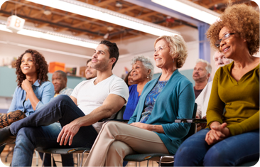 A diverse audience sitting in chairs and looking attentively off-camera.
