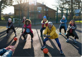 A diverse group of mature female netball players engaging in an outdoor session.
