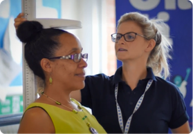 A healthcare professional measures a woman's height during a health checkup.