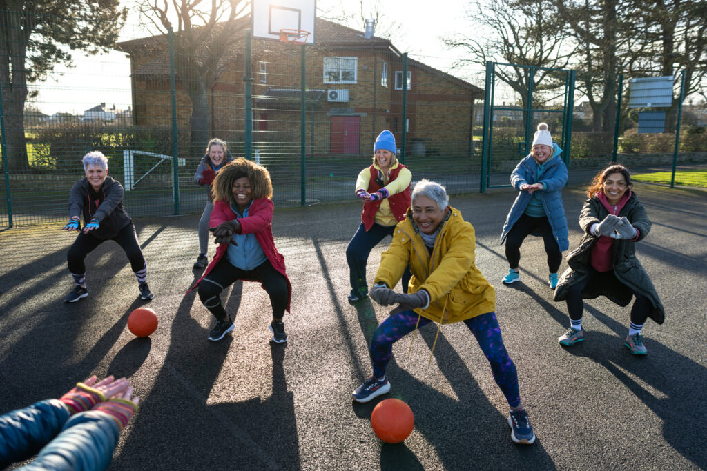 A diverse group of mature female netball players engaging in an outdoor session.
