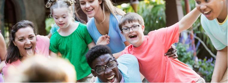 A group of smiling friends standing in a circle, with their arms raised together