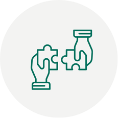 Two green-outlined hands fitting together interlocking puzzle pieces on a light grey circle background.
